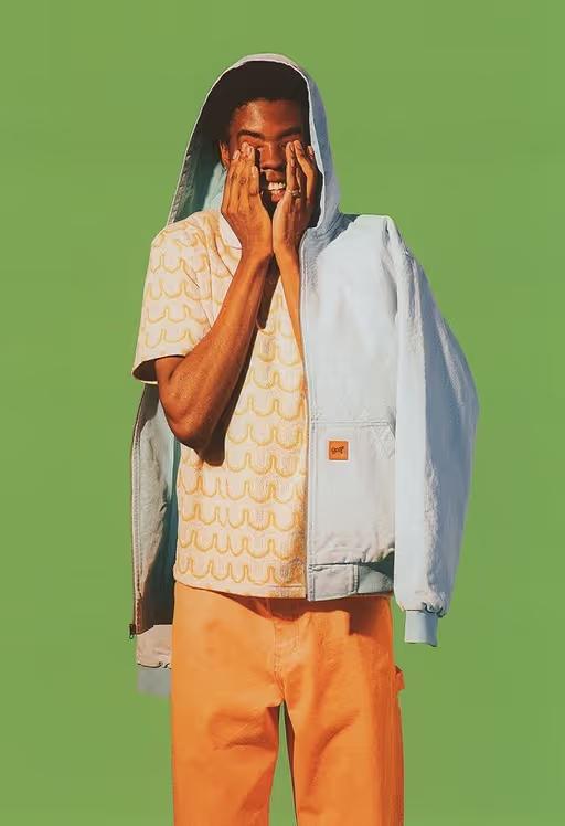 A man wearing a Golf Wang baby blue jacket and an orange button up with matching pants