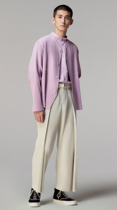 A man wearing an Issey Myake pink cardigan with beige slacks