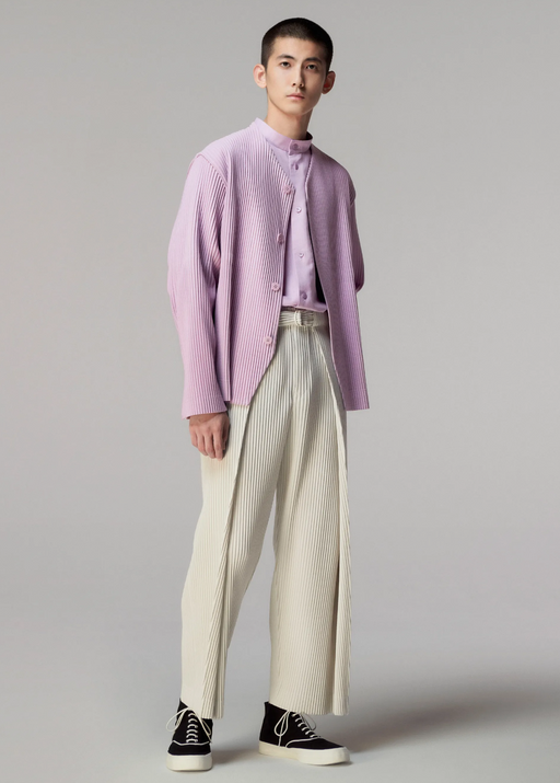 A man wearing an Issey Myake pink cardigan with beige slacks