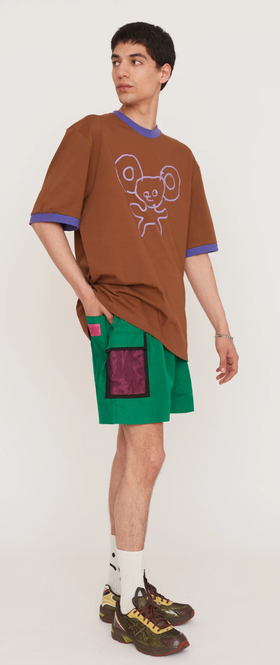 A man wearing a Lazy Oaf brown shirt and green shorts