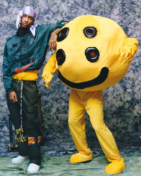 A man wearing a Cactus Plant Flea Market outfit with a yellow mascot