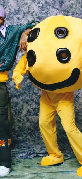A man wearing a Cactus Plant Flea Market outfit with a yellow mascot