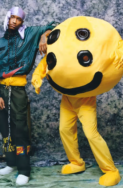 A man wearing a Cactus Plant Flea Market outfit with a yellow mascot