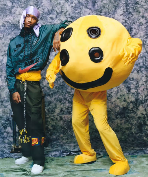 A man wearing a Cactus Plant Flea Market outfit with a yellow mascot