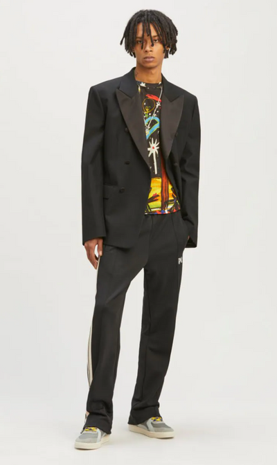 A man wearing a Palm Angels black suit with a graphic t-shirt underneath