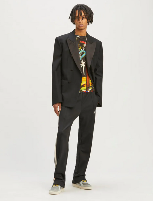 A man wearing a Palm Angels black suit with a graphic t-shirt underneath