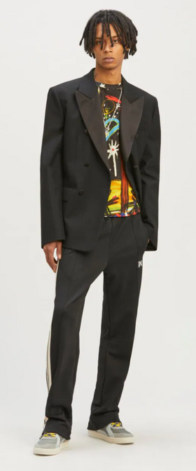 A man wearing a Palm Angels black suit with a graphic t-shirt underneath