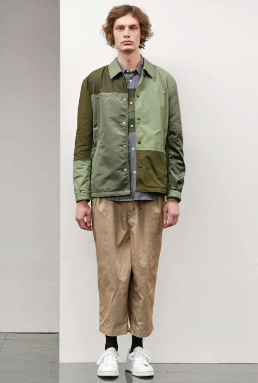 A man wearing a green Comme Des Garcons jacket with brown pants