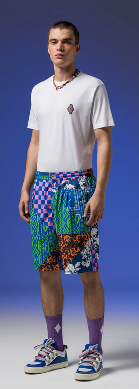 A man wearing Macelo Burlon County of Milan graphic shorts with a white t-shirt