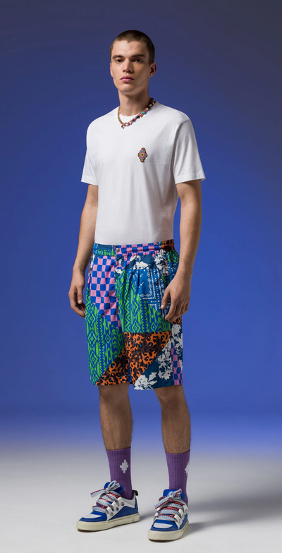 A man wearing Macelo Burlon County of Milan graphic shorts with a white t-shirt