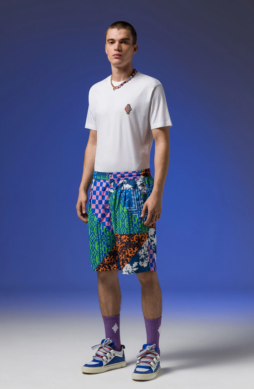 A man wearing Macelo Burlon County of Milan graphic shorts with a white t-shirt