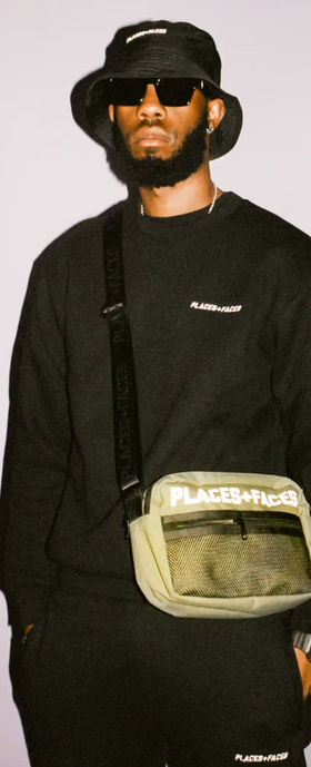 A man wearing a Places+Faces black crewneck, matching bucket hat and branded side-bafg