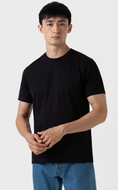 A man wearing a black Sunspel t-shirt with jeans