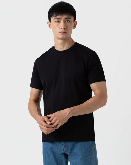 A man wearing a black Sunspel t-shirt with jeans