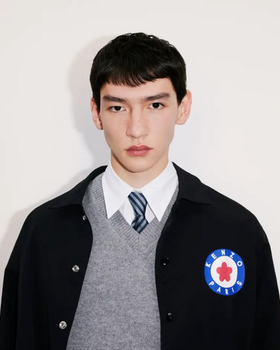 A young man wearing a school uniform with a Kenzo jacket