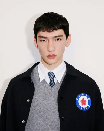 A young man wearing a school uniform with a Kenzo jacket