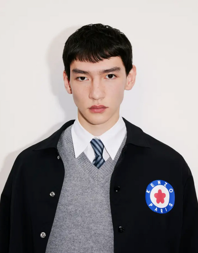 A young man wearing a school uniform with a Kenzo jacket