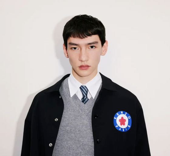 A young man wearing a school uniform with a Kenzo jacket