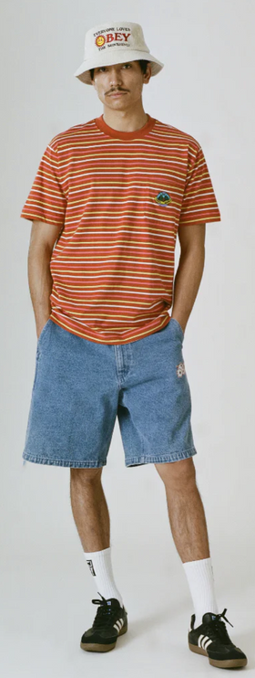 A man wearing a striped obey t-shirt with a branded bucket hat and denim shorts