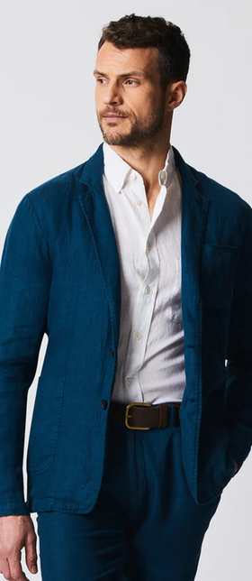 A man wearing a Billy Reid navy blue suit and white button up shirt