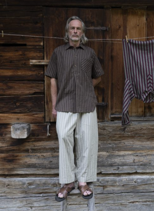 A man wearing a Frank Leder brown button up t-shirt and white loose pants