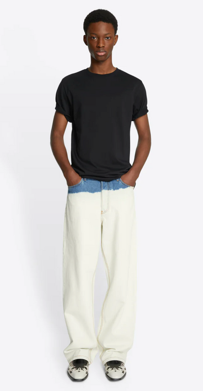 A man wearing a slim fit Dries Van Noten navy blue t-shirt with baggie white denim