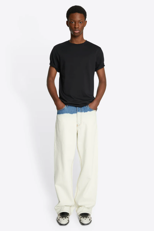 A man wearing a slim fit Dries Van Noten navy blue t-shirt with baggie white denim