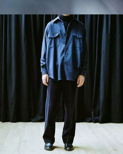 A man wearing a Comoli outfit featuring navy blue pants and a denim top