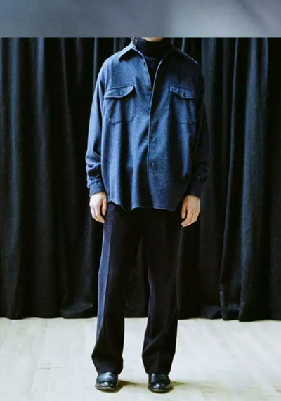A man wearing a Comoli outfit featuring navy blue pants and a denim top