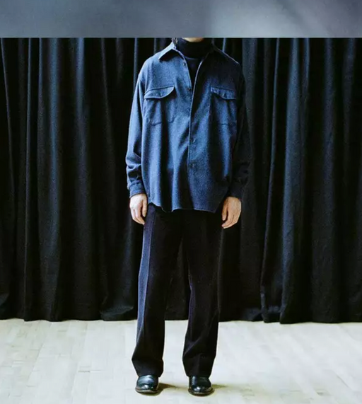 A man wearing a Comoli outfit featuring navy blue pants and a denim top
