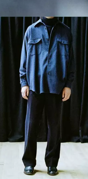 A man wearing a Comoli outfit featuring navy blue pants and a denim top