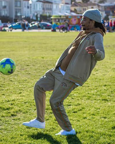 A man volleying a soccer ball while wearing a LRG clothing outfit