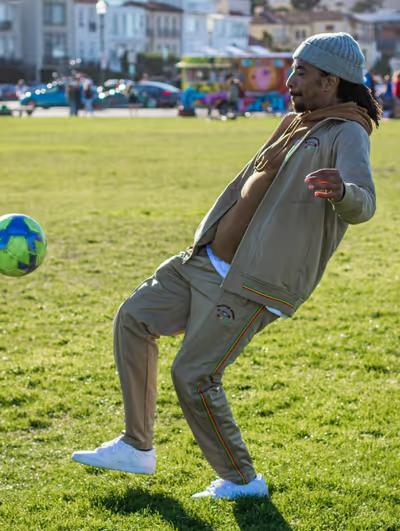 A man volleying a soccer ball while wearing a LRG clothing outfit