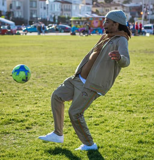 A man volleying a soccer ball while wearing a LRG clothing outfit