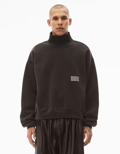 A man wearing an Alexander Wang logo fleece with black pants
