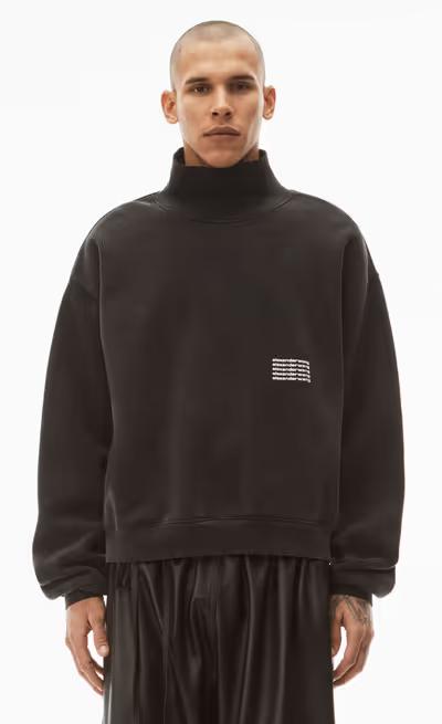 A man wearing an Alexander Wang logo fleece with black pants