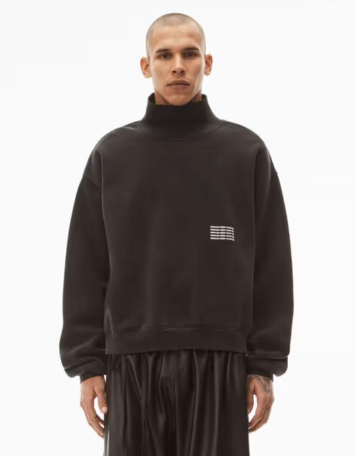 A man wearing an Alexander Wang logo fleece with black pants