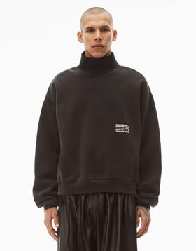 A man wearing an Alexander Wang logo fleece with black pants