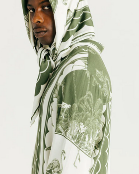 A man wearing a Ih Nom Uh Nit hoodie in green bandana