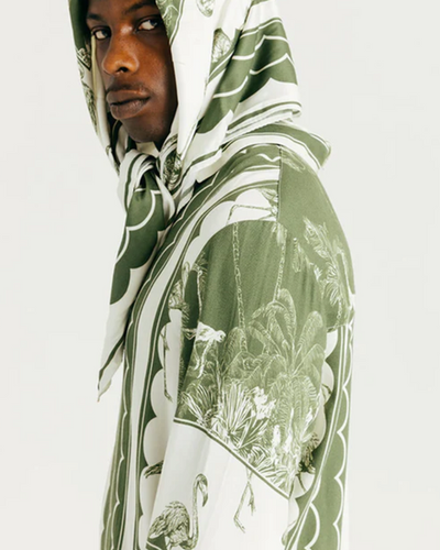 A man wearing a Ih Nom Uh Nit hoodie in green bandana