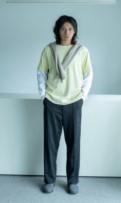 A man wearing a Lady White Co t-shirt and pants with a sweater draped over