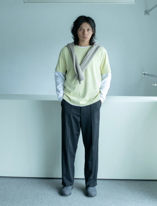 A man wearing a Lady White Co t-shirt and pants with a sweater draped over
