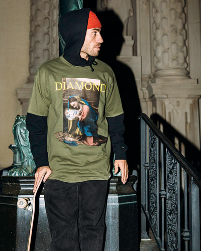 A man wearing a graphic Diamond Supply Co. t-shirt with a skateboard in hand