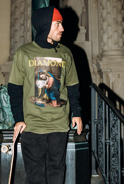 A man wearing a graphic Diamond Supply Co. t-shirt with a skateboard in hand
