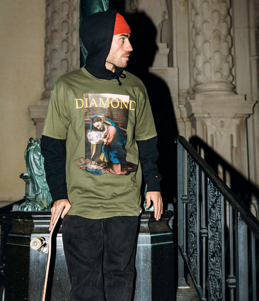A man wearing a graphic Diamond Supply Co. t-shirt with a skateboard in hand