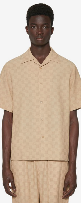 A man wearing a beige all over print MISBHV outfit with a matching shirt and pants