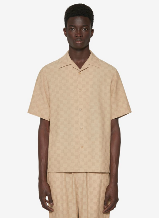 A man wearing a beige all over print MISBHV outfit with a matching shirt and pants
