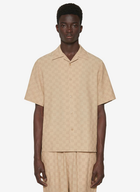 A man wearing a beige all over print MISBHV outfit with a matching shirt and pants