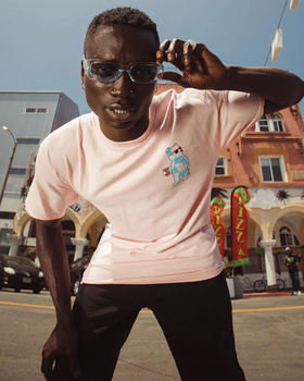 A man wearing a pink Riot Society t-shirt and sunglasses