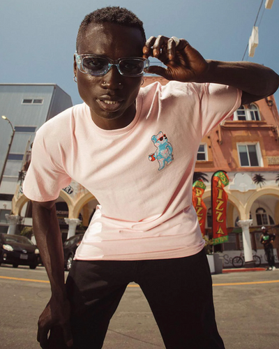 A man wearing a pink Riot Society t-shirt and sunglasses